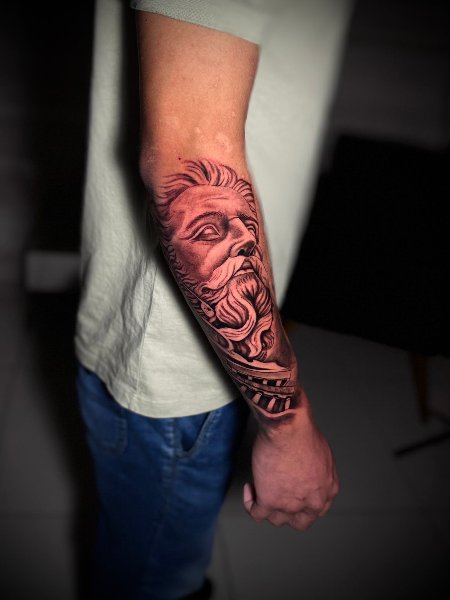 Black and grey realism Zeus statue tattoo on the forearm